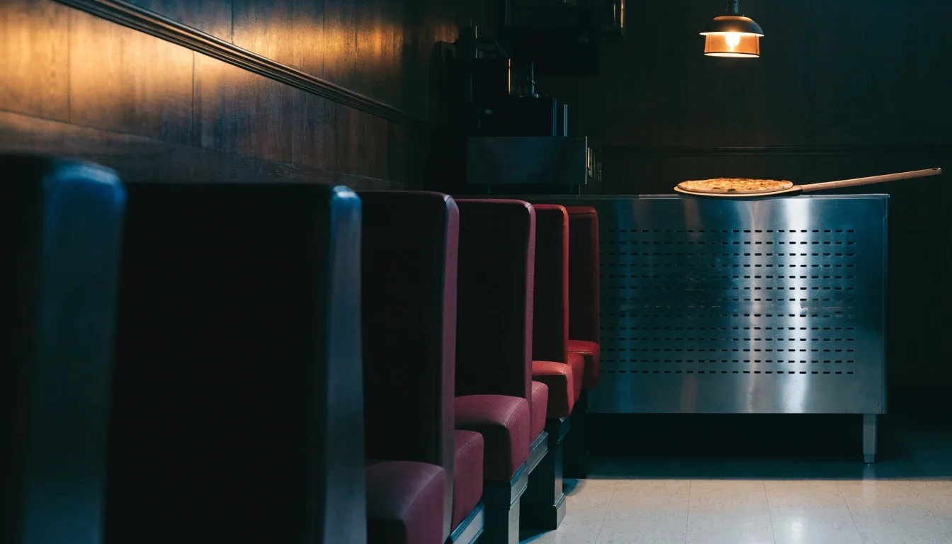 An empty Papa Gino's dining room at night, with the pizza pass lit under a single overhead lamp